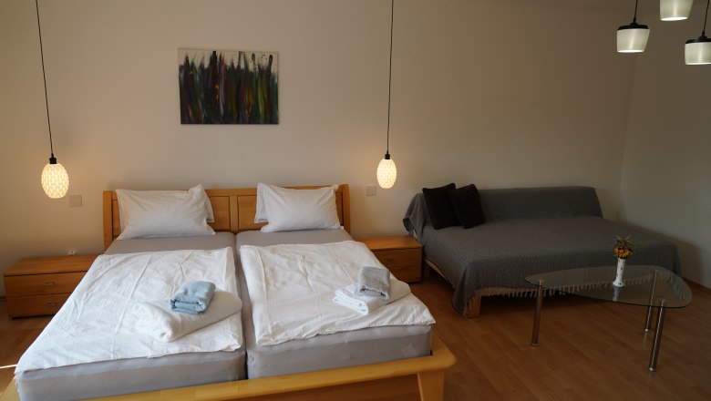 Gem&uuml;tliches Schlafzimmer mit Doppelbett, Sofa und Glastisch.