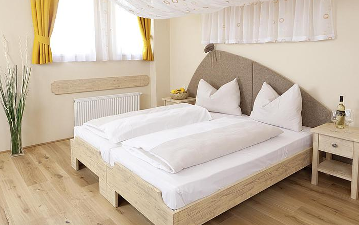 Ein gemütliches Gästezimmer mit Doppelbett, gelben Vorhängen und Holzmöbeln.