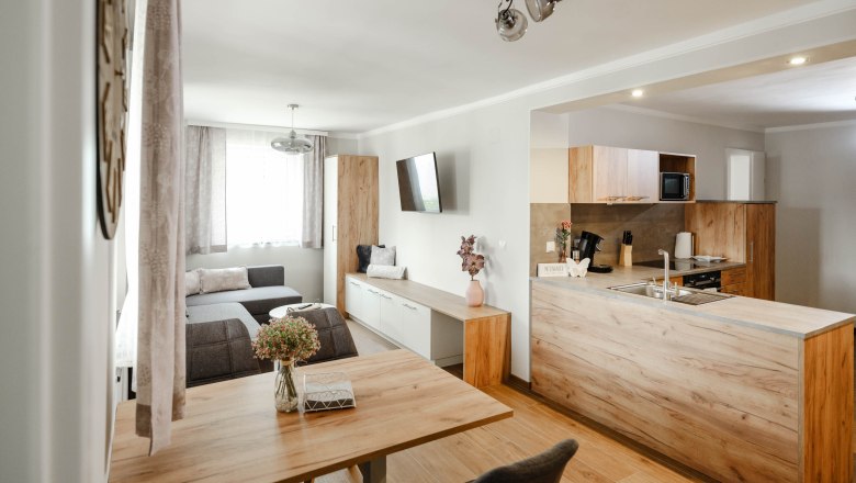 Moderne Wohnküche mit Holzmöbeln und grauem Sofa.