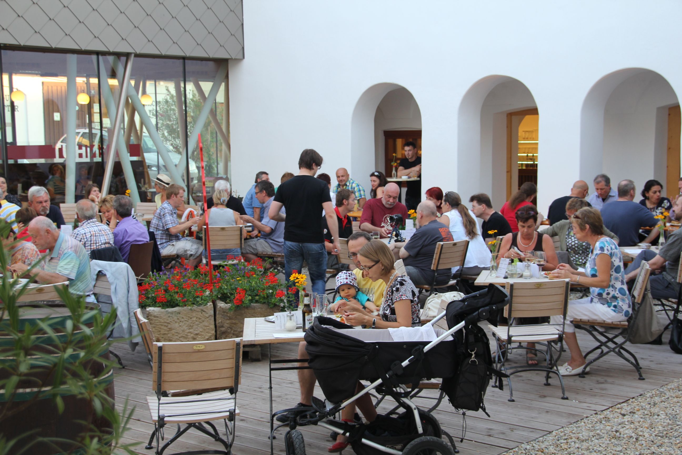 Menschen sitzen in einem Innenhof an Tischen und essen.
