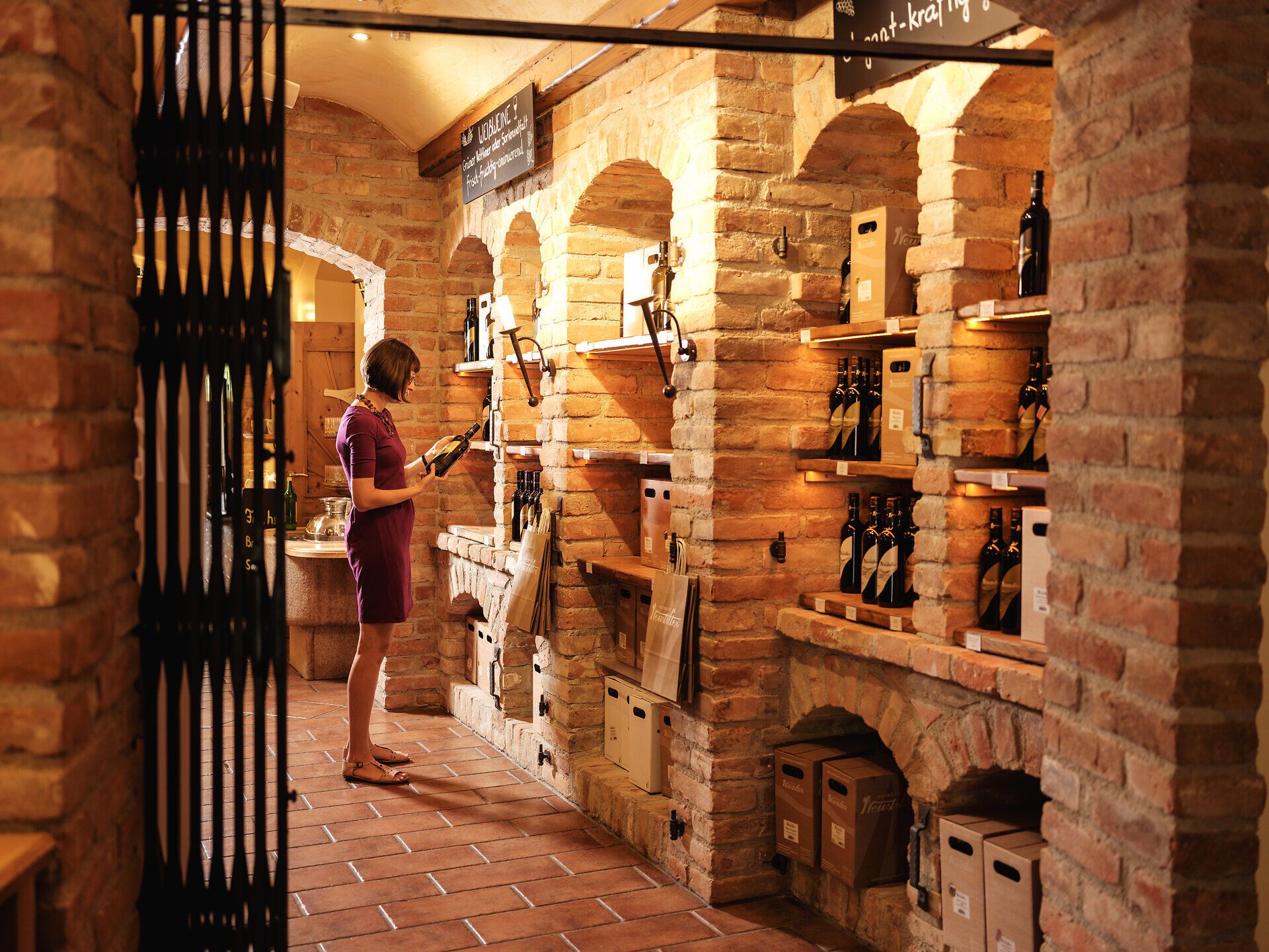 In der gemütlichen Vinothek umgeben von warmem Ziegelstein und sanftem Licht, genießt man die erlesenen Weine der Region. Die Atmosphäre ist geprägt von der Vorfreude auf die Weinlese, während die Aromen der Trauben in der Luft liegen und die Sinne betören.