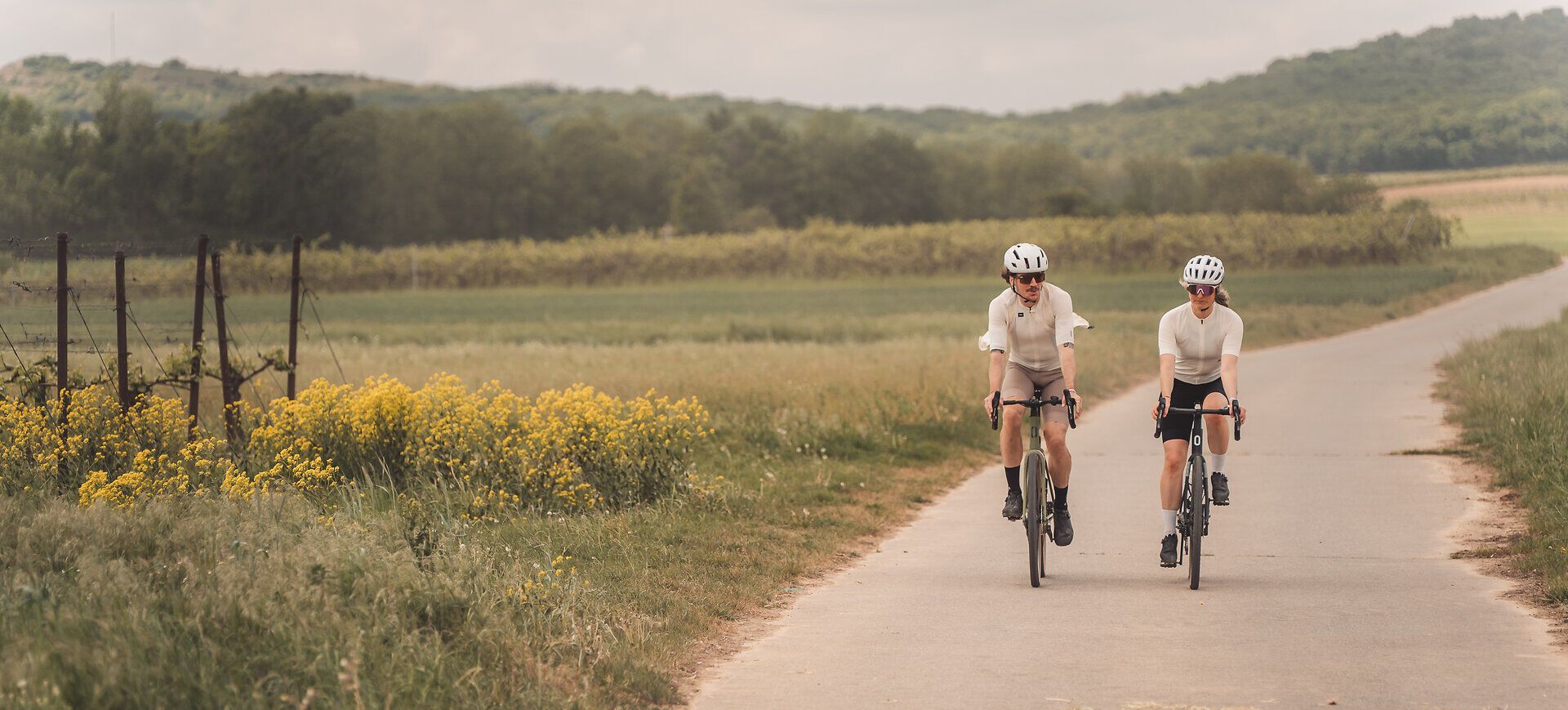 Zwei Radfahrer sind auf Gravelbikes in der Weinviertler Landschaft unterwegs.