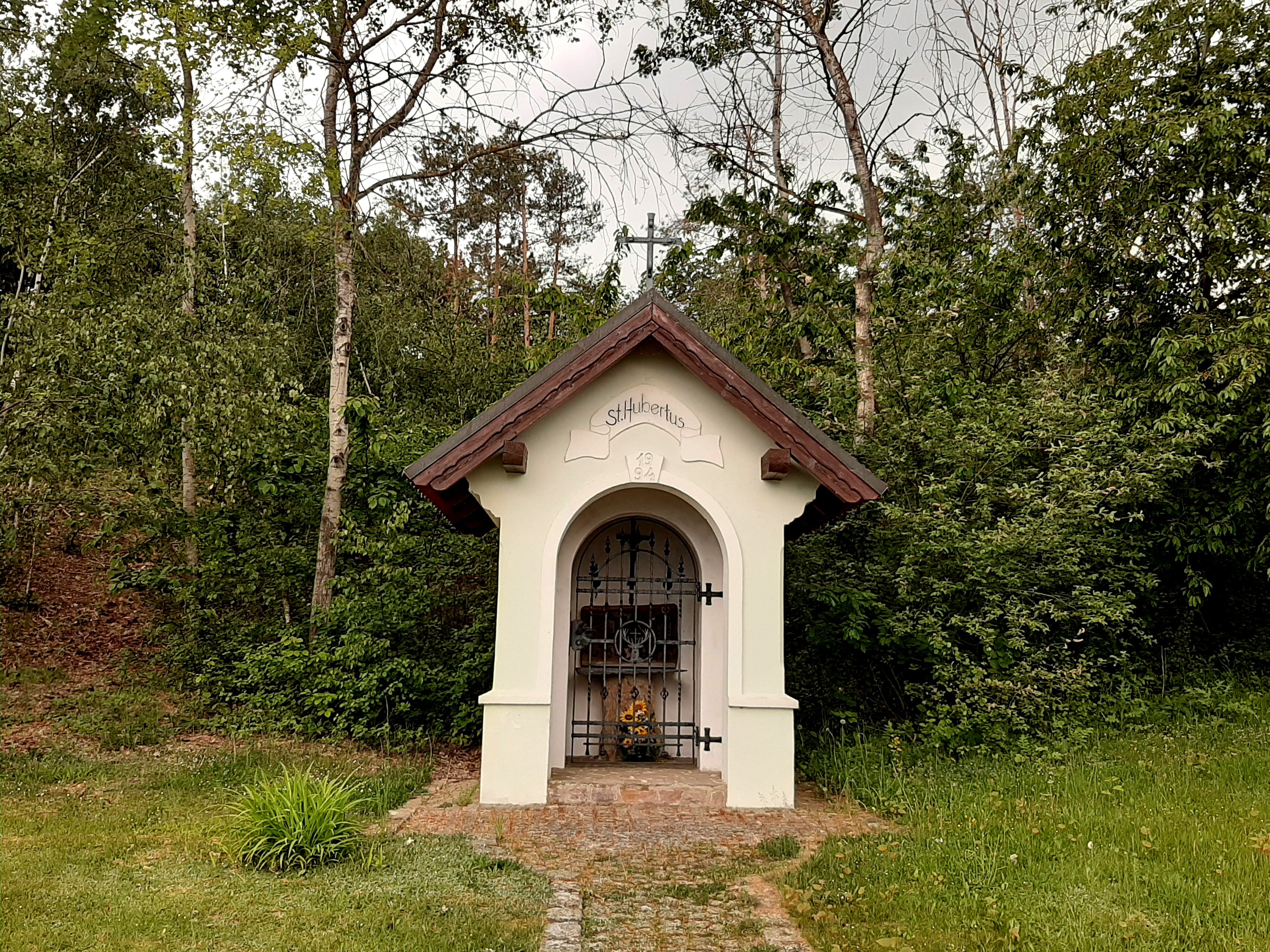 Kleine Kapelle im Wald mit der Aufschrift 'St. Hubertus'.