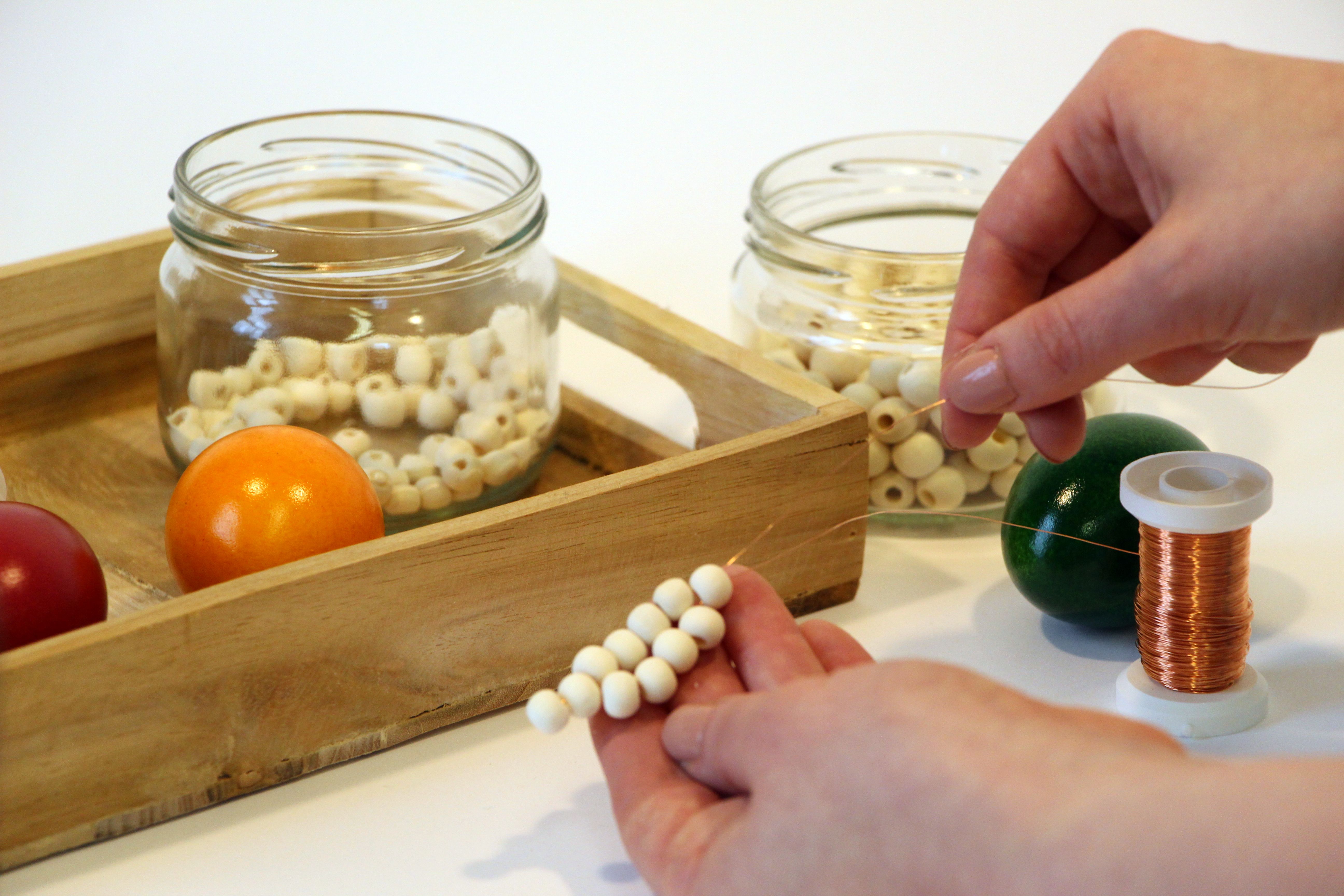 Auf Draht sind Holzperlen aufgefädelt.