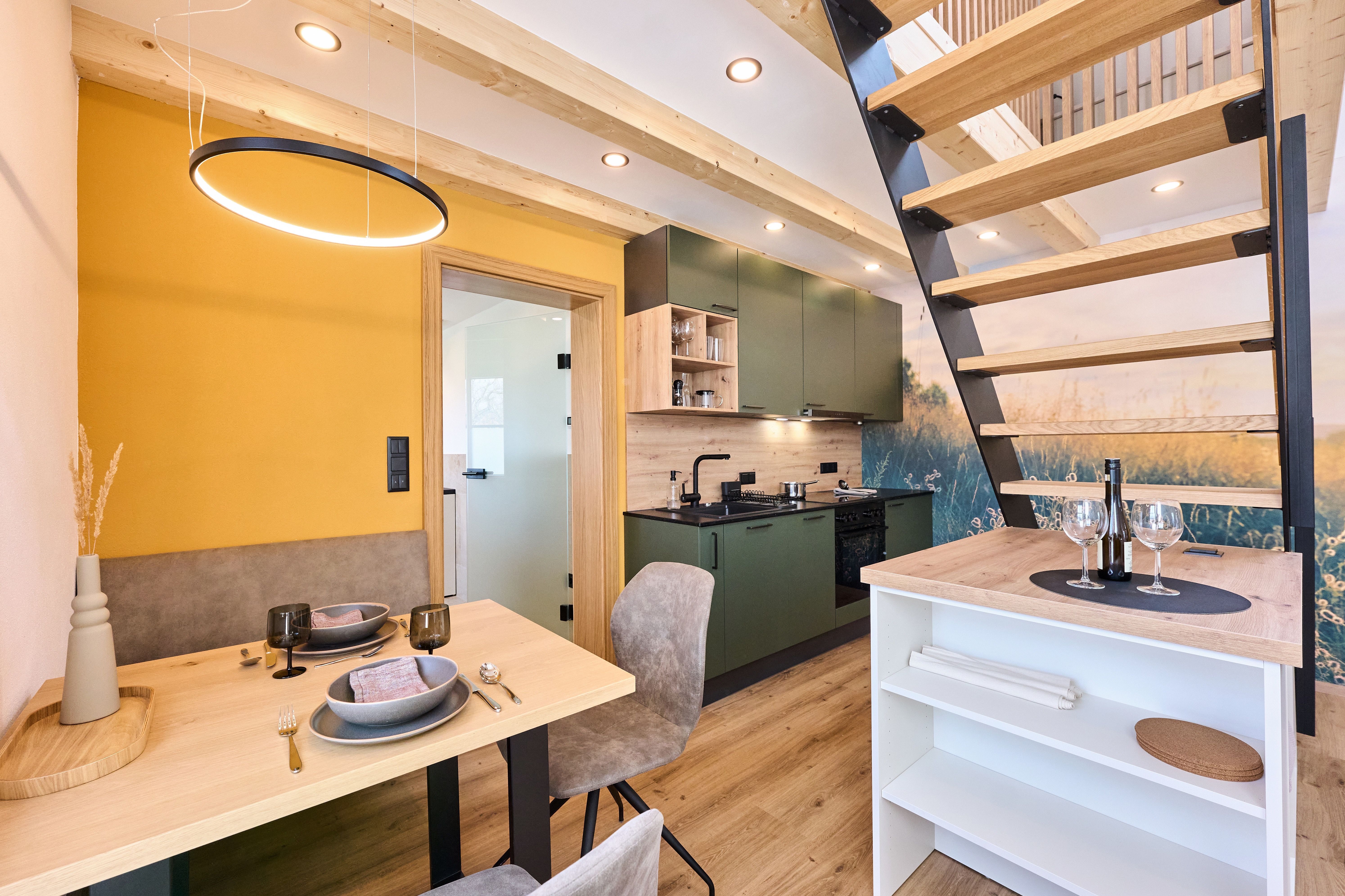 Modernes Interieur eines kleinen Hauses mit Küche, Esstisch und Treppe.