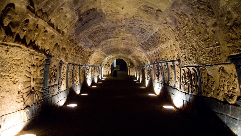 Ein beleuchteter, gewölbter Tunnel mit kunstvollen Reliefs an den Wänden.