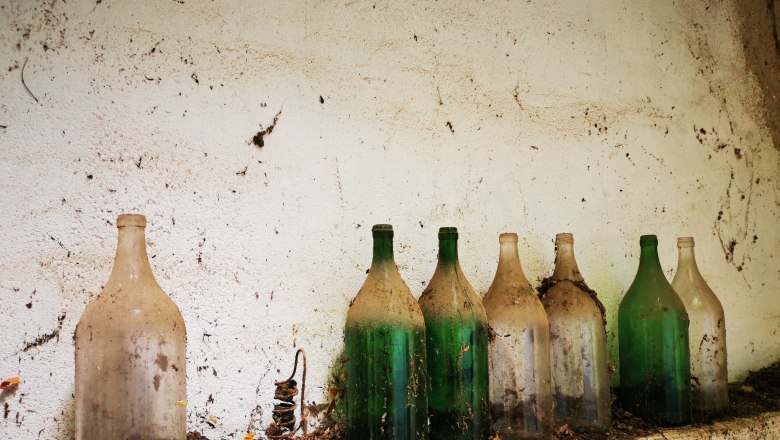 Old, dusty glass bottles on a shelf in a cellar.