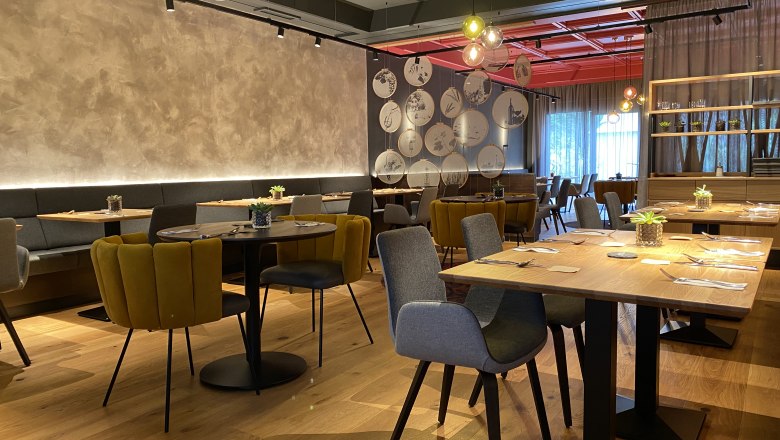 Modernes Restaurant mit stilvoller Einrichtung, Holztischen und gemütlichen Stühlen.