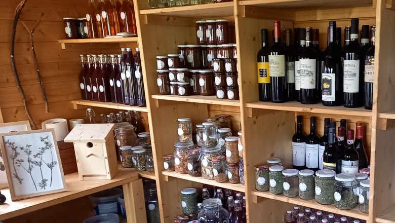 Regale mit Flaschen, Gläsern und Wein in einem Holzladen.