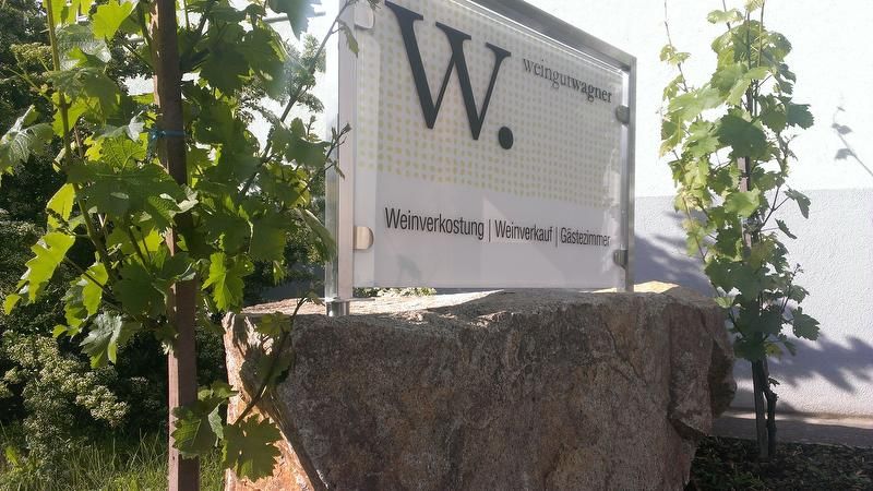 Schild des Weinguts Wagner mit Weinreben im Hintergrund.