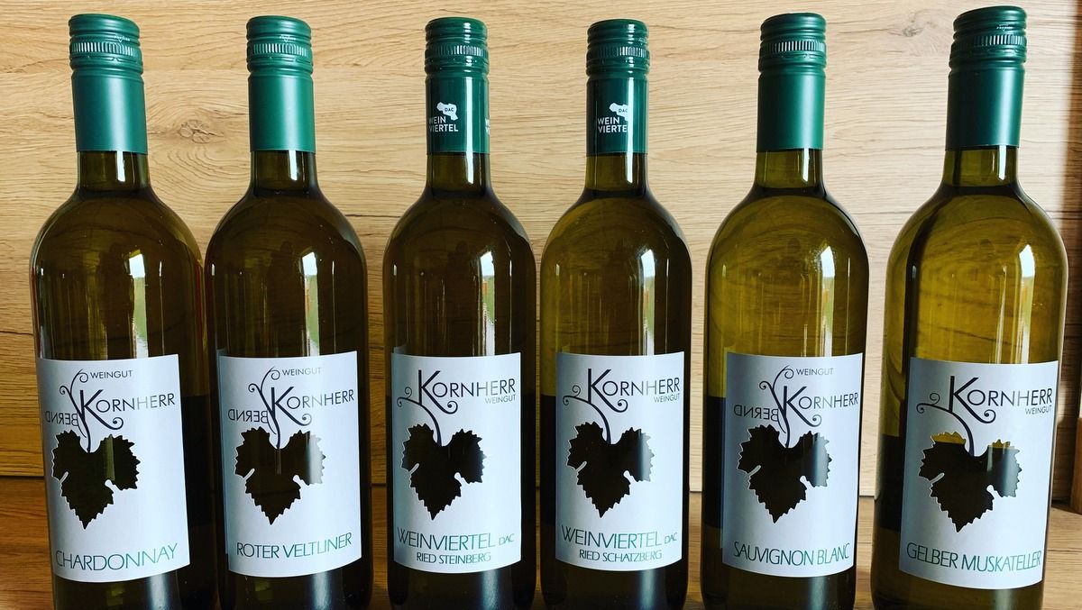Six bottles of wine from the Kornherr winery on a wooden table.