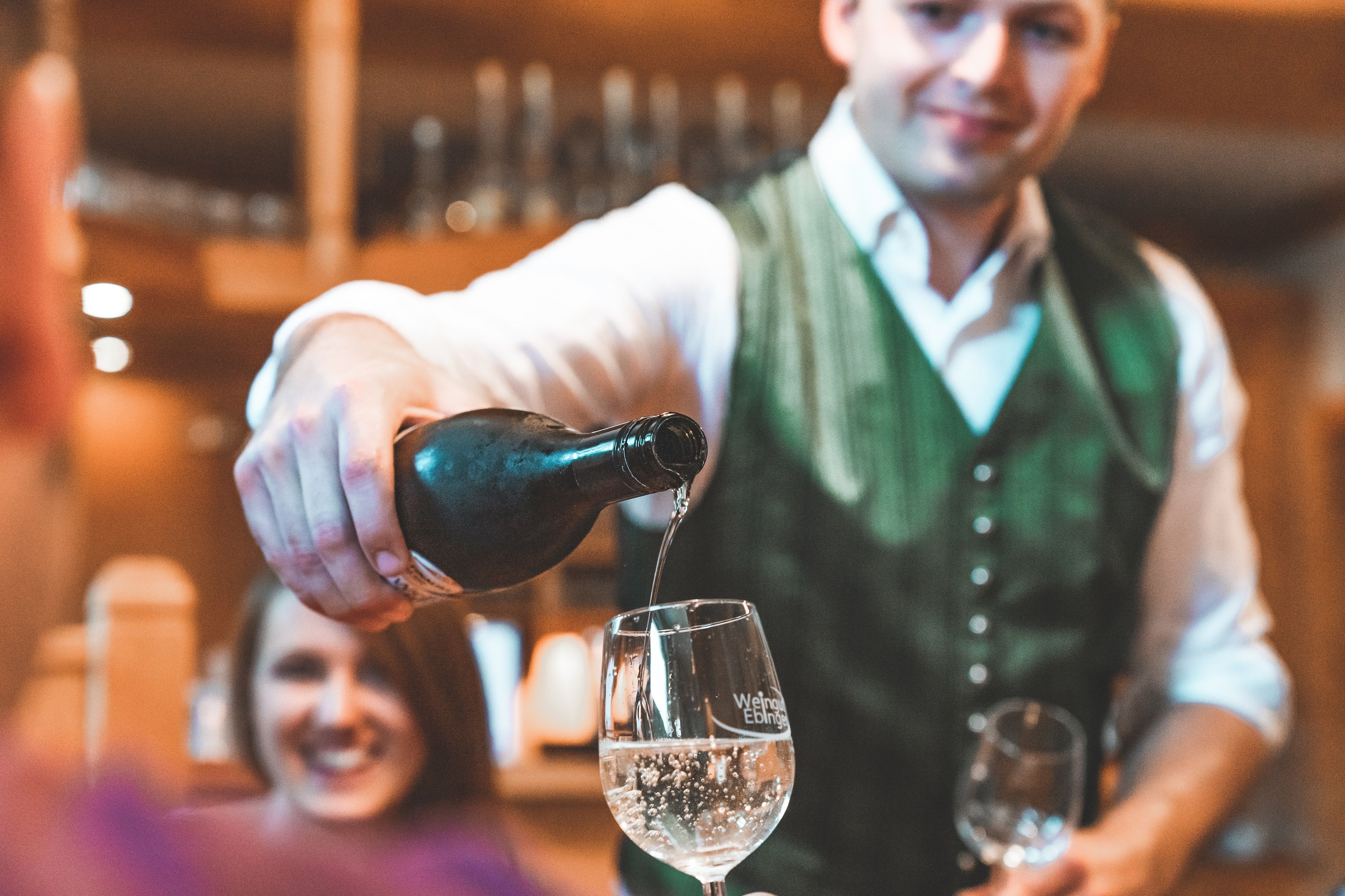 Ein Mann in traditioneller Kleidung schenkt Wein in ein Glas ein.