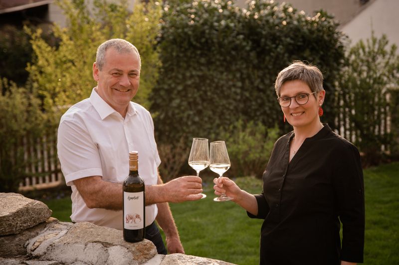 A man and a woman clink glasses of wine in the garden.