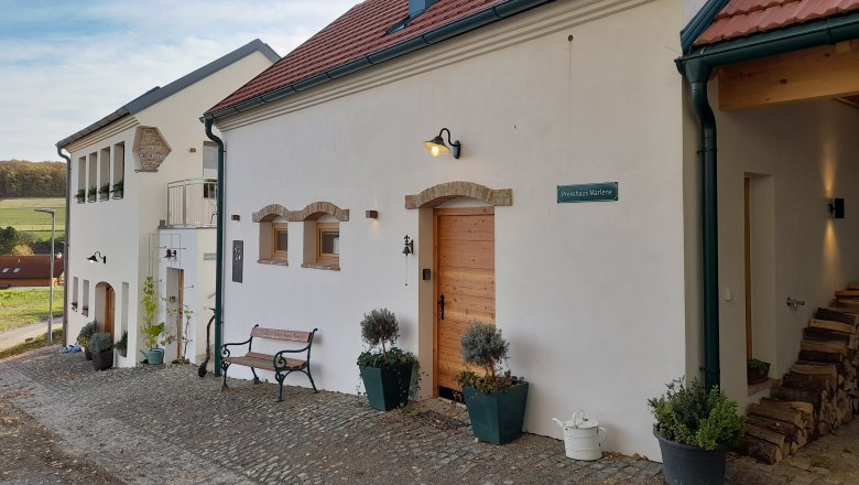 Ein renoviertes Gebäude mit roten Ziegeldächern und weißer Fassade auf einem Biohof.