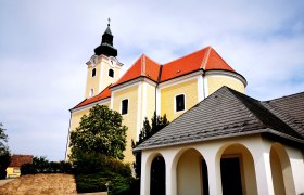 Pfarrkirche St. Nikolaus in Röschitz mit gelber Fassade und rotem Dach.