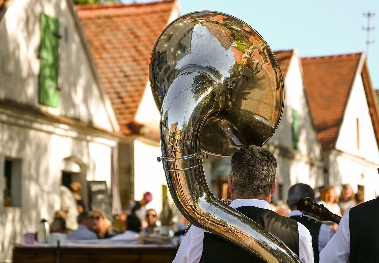 Ein festlicher Klang erfüllt die Luft, während die Musikanten mit ihren Instrumenten die Besucher in eine fröhliche Stimmung versetzen. Umgeben von charmanten Weinhäusern und der malerischen Landschaft, genießen die Gäste die köstlichen Weine und die kulturellen Darbietungen des Kellergassenfests.