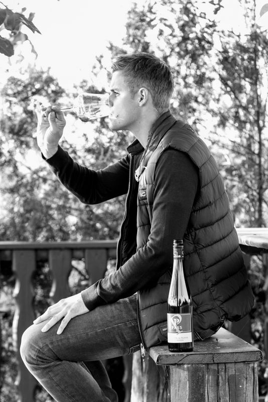 Mann trinkt Wein auf einer Terrasse.