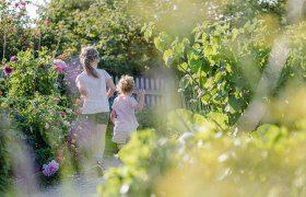 Zwei Kinder laufen durch einen blühenden Gartenweg im Museumsdorf Niedersulz.