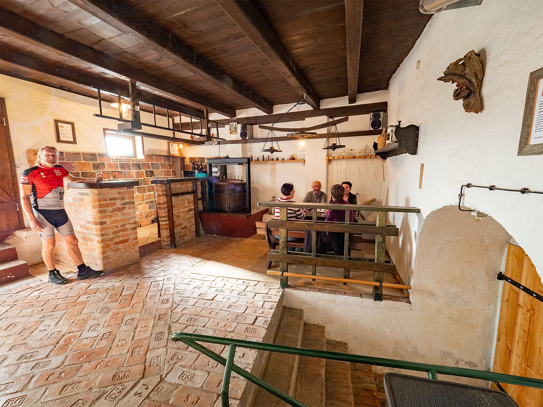 Cozy wine cellar with people at a table and a man in cycling clothes.