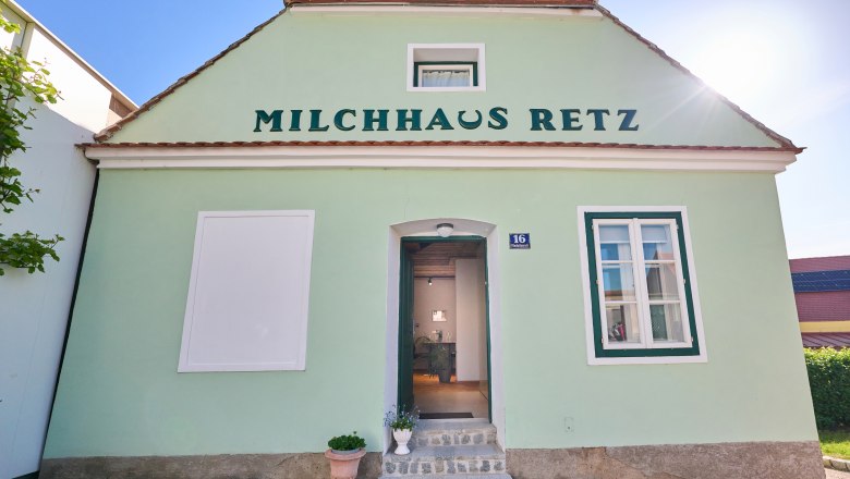Gr&uuml;nes Geb&auml;ude mit der Aufschrift 'Milchhaus Retz' und einer offenen T&uuml;r.