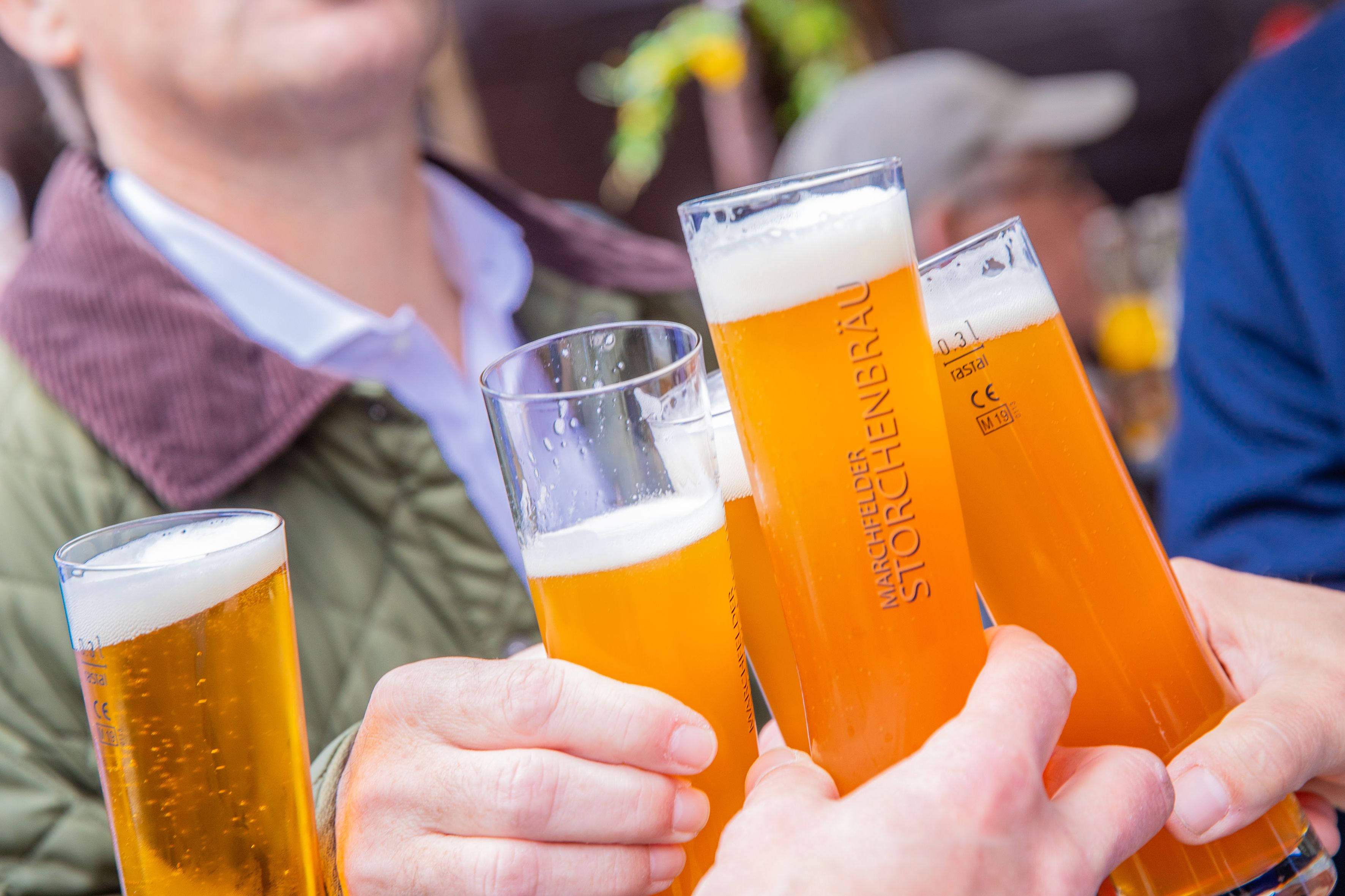 Personen stoßen mit Bier an.