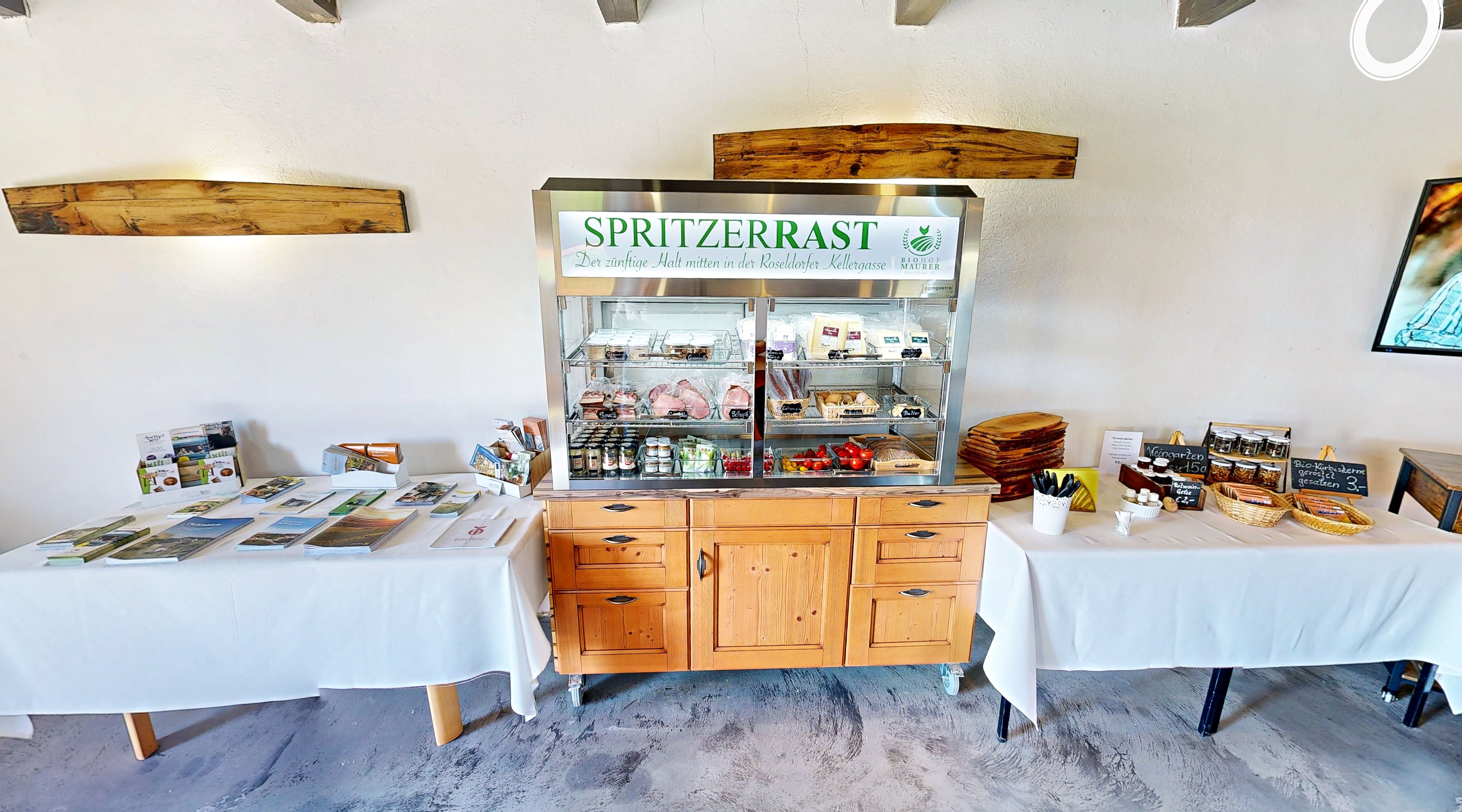 Ein Verkaufsstand mit regionalen Produkten und Informationsmaterialien in einem Raum mit Holzmöbeln.