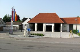 Außenansicht des Ziegelmuseums in Ziersdorf mit roten Dachziegeln und Flaggen.