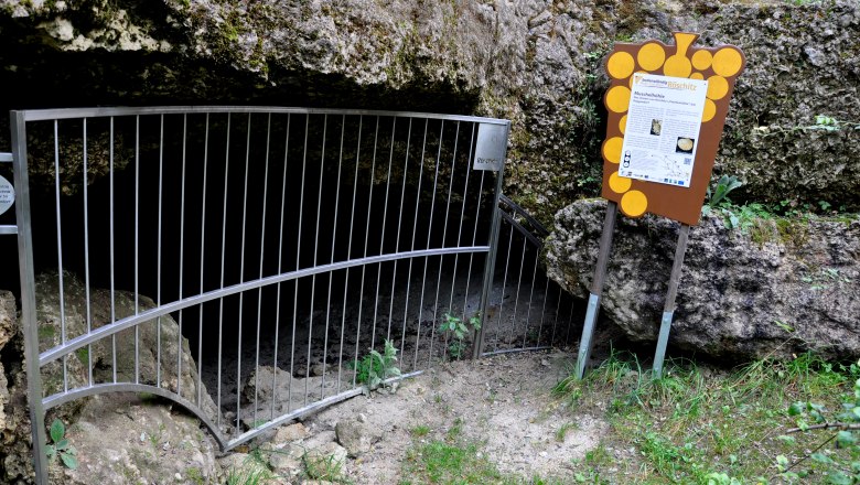 Eingang zur Muschelhöhle Röschitz mit Gitter und Infotafel.