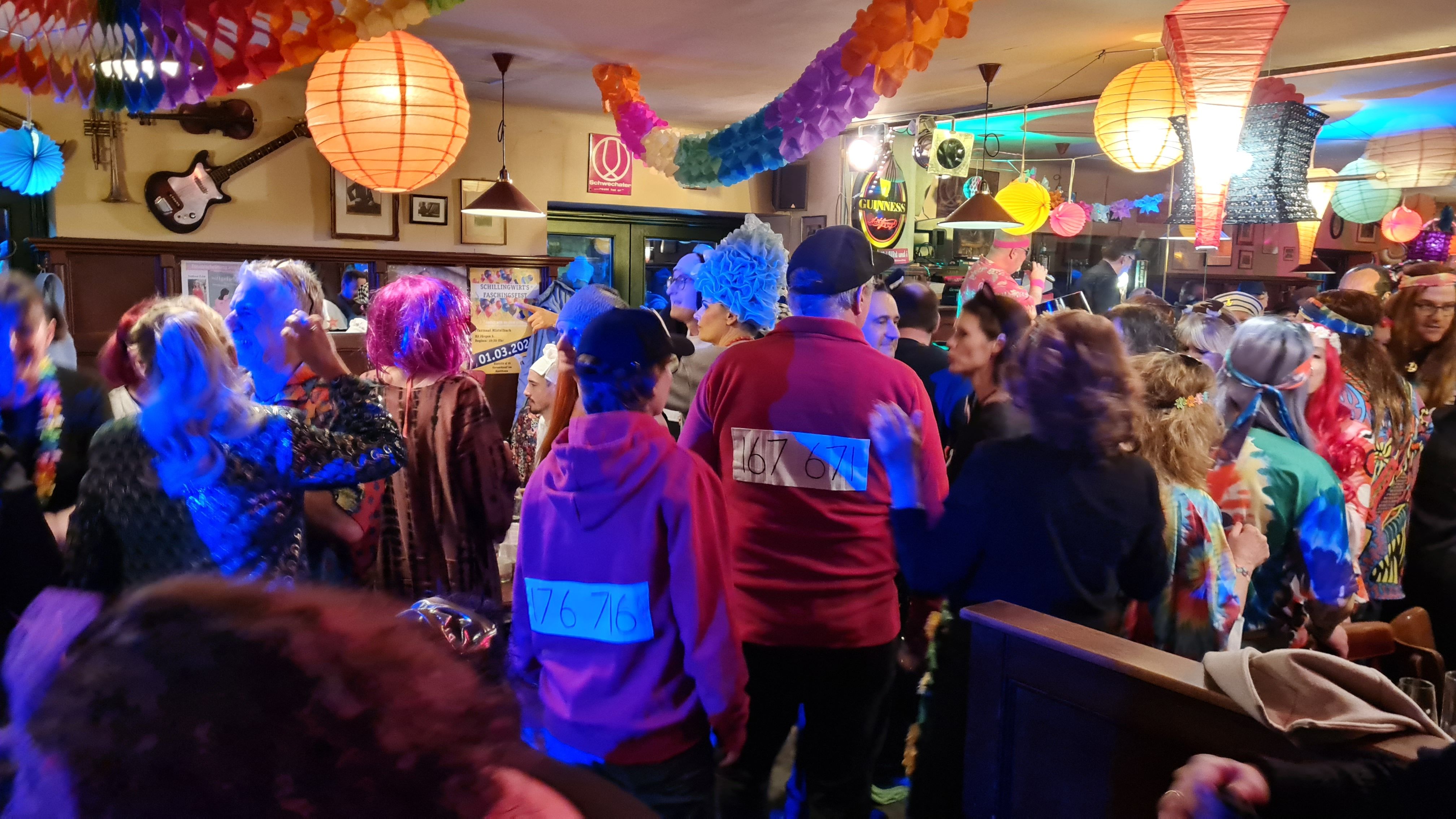 Menschen in bunten Kostümen feiern Fasching in einem dekorierten Raum.