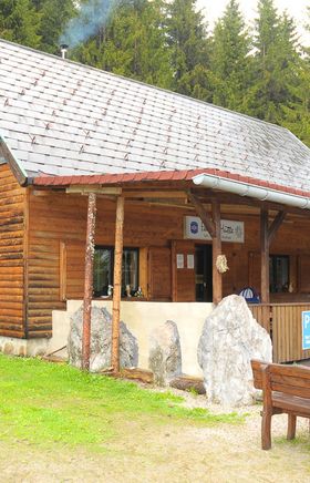 bewirtschaftet Holzhütte am Preiner Gscheid, davor ein Dachvorsprung und Holztische und Bänke