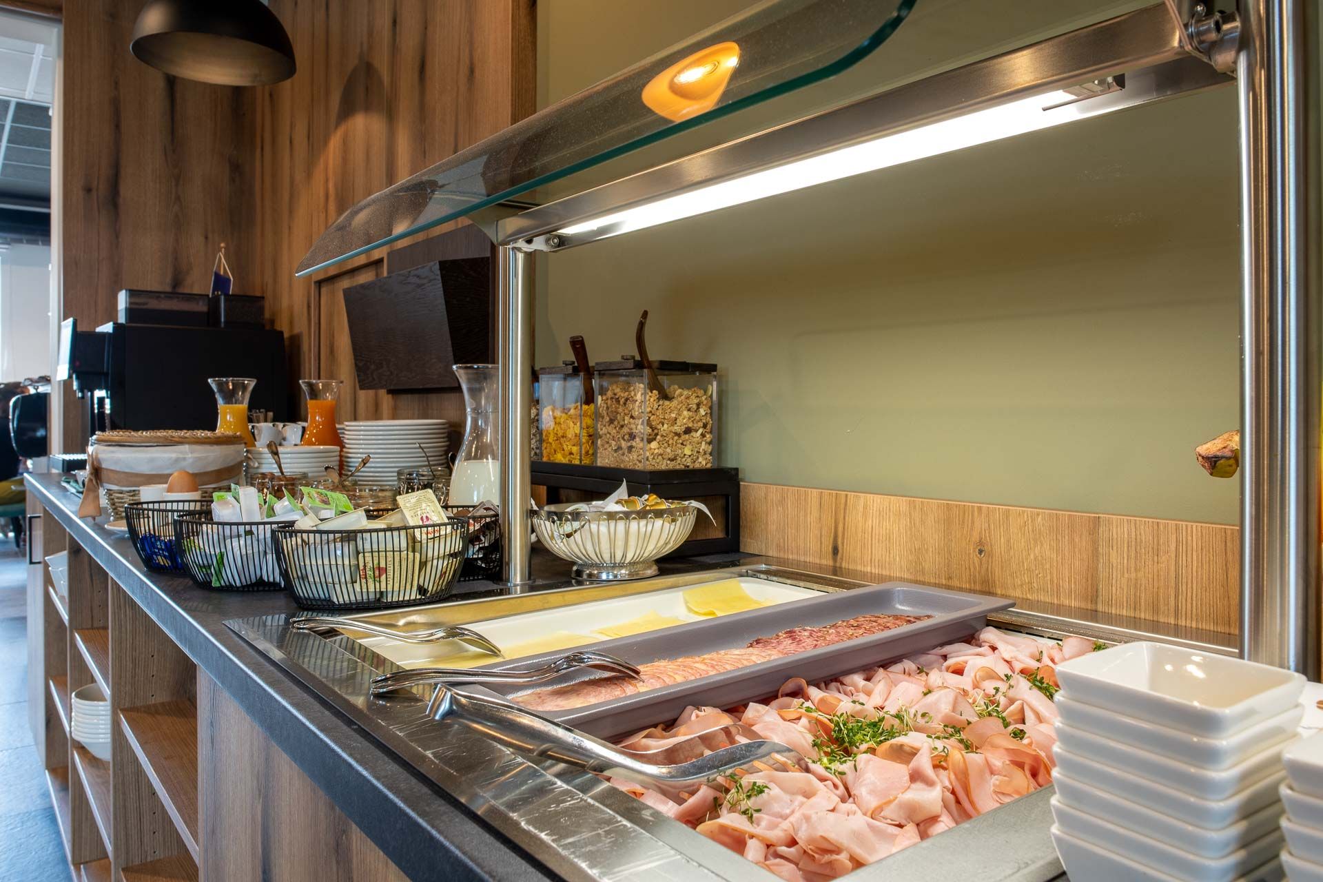 Frühstücksbuffet mit Aufschnitt, Käse, Müsli und Getränken.