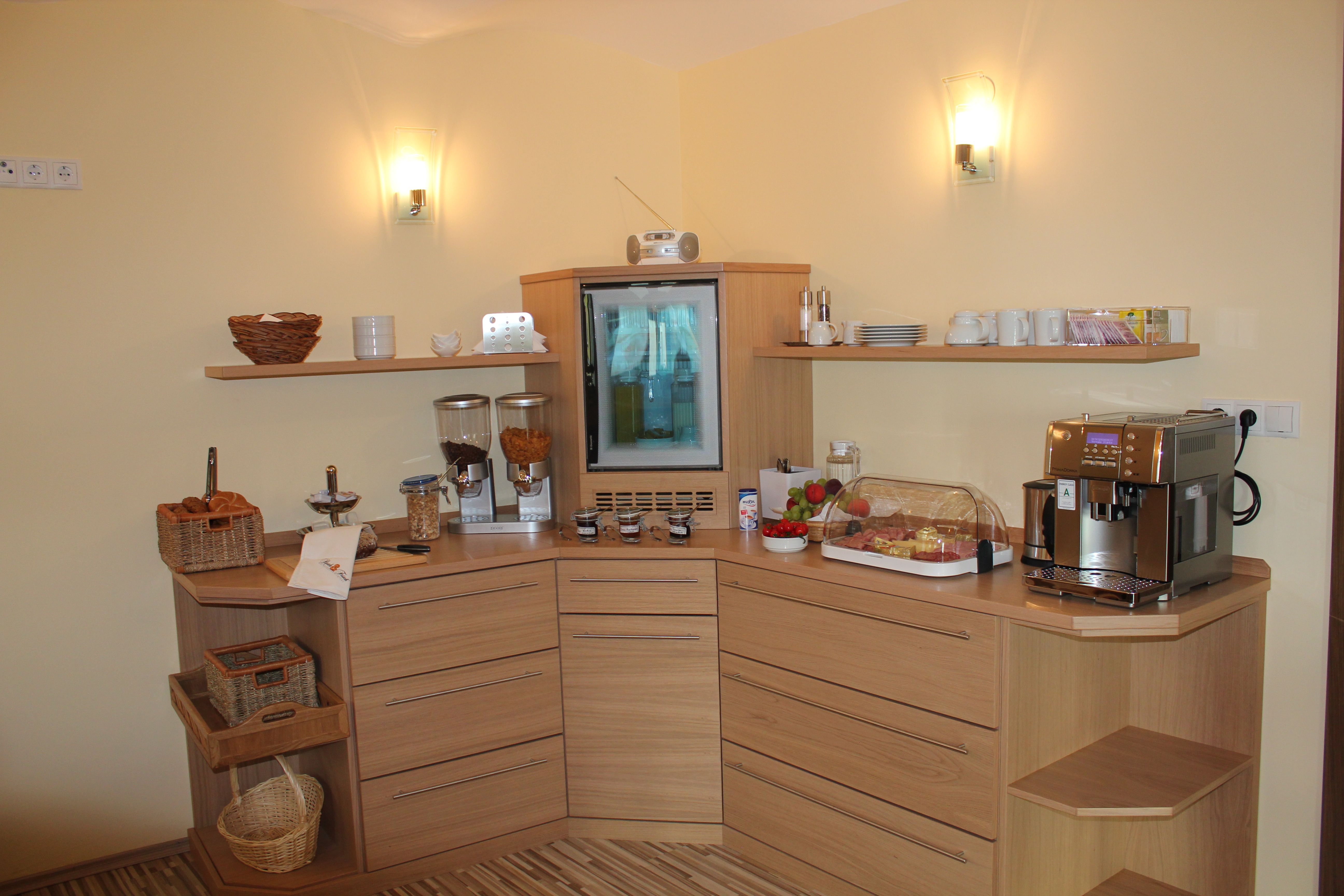 Frühstücksbuffet in einem Gästehaus mit Kaffeeautomat, Müsli, Obst und Aufschnitt.