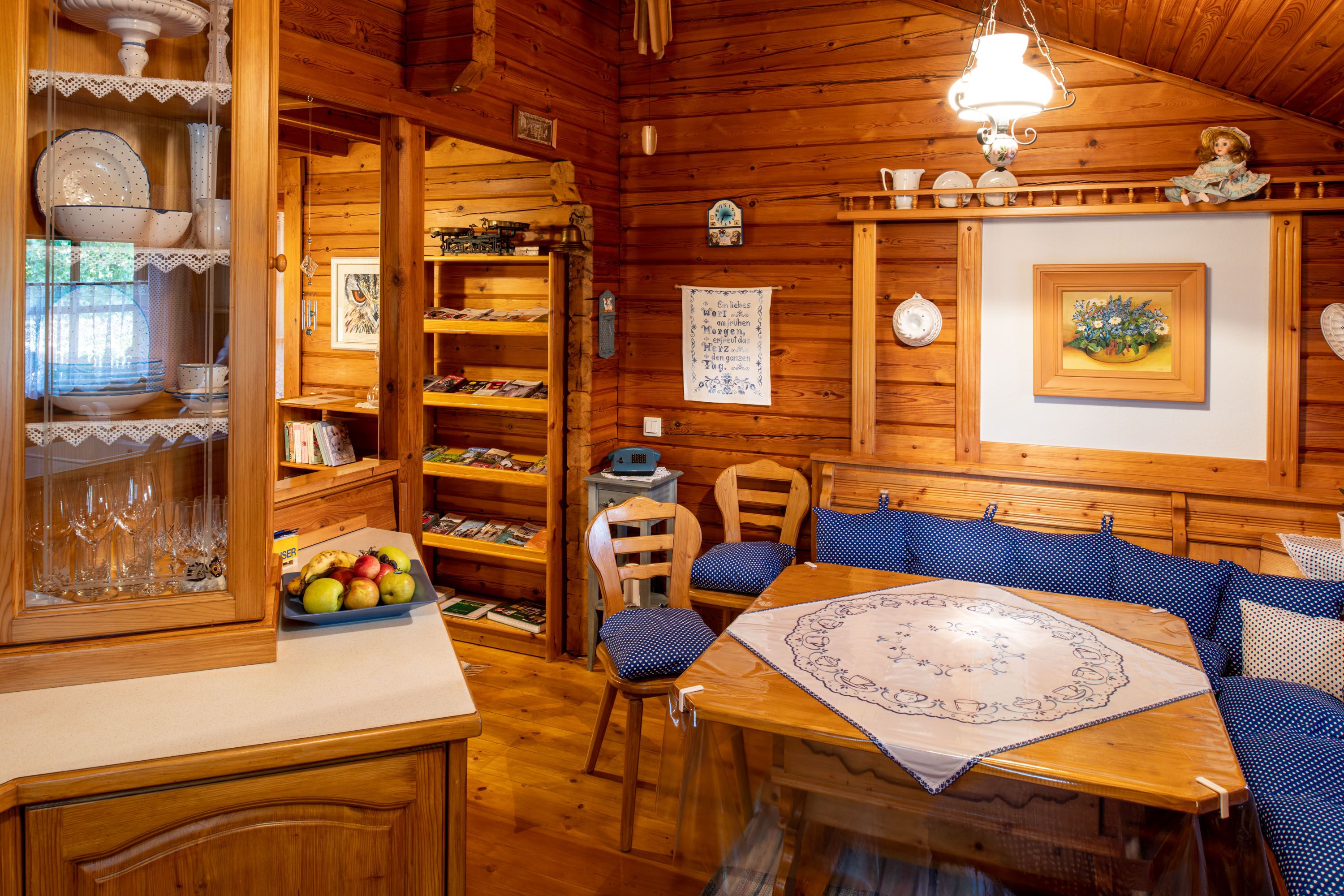 Gemütliche Holzhütte mit Esstisch, blauen Polstern und Dekorationen.