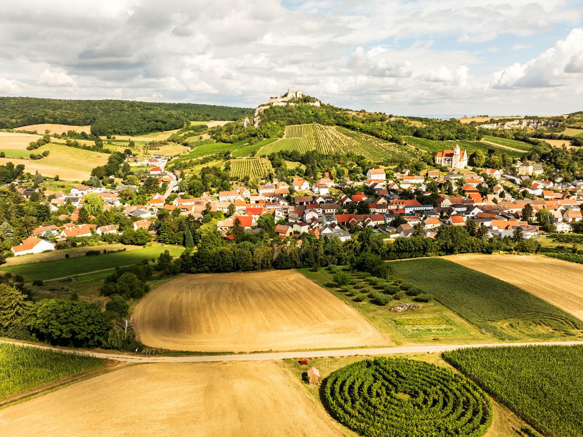 Luftaufnahme von Falkenstein mit Weinbergen und Feldern im Vordergrund.