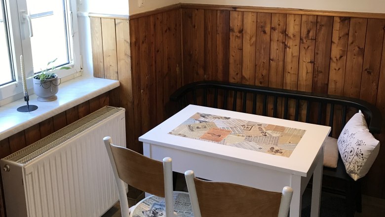 Kleine Essecke mit Tisch, St&uuml;hlen und Bank in einer K&uuml;che mit Holzvert&auml;felung.