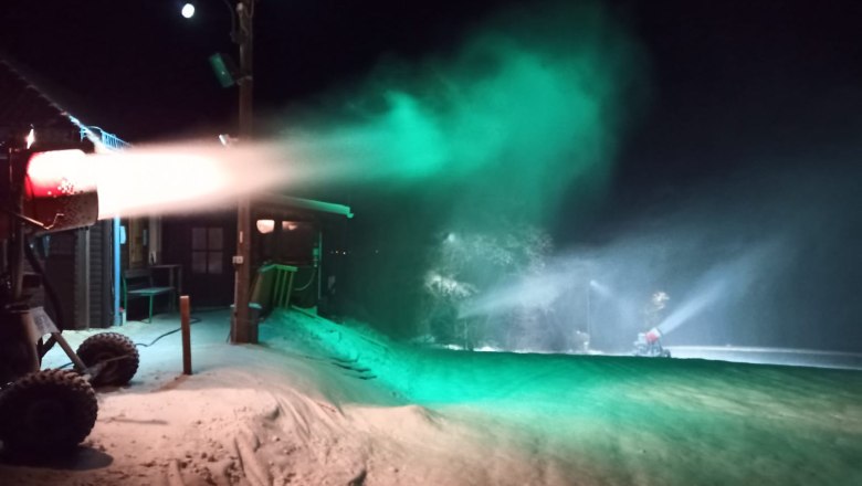 Schneekanone bei Nacht mit grünem Licht beleuchtet.