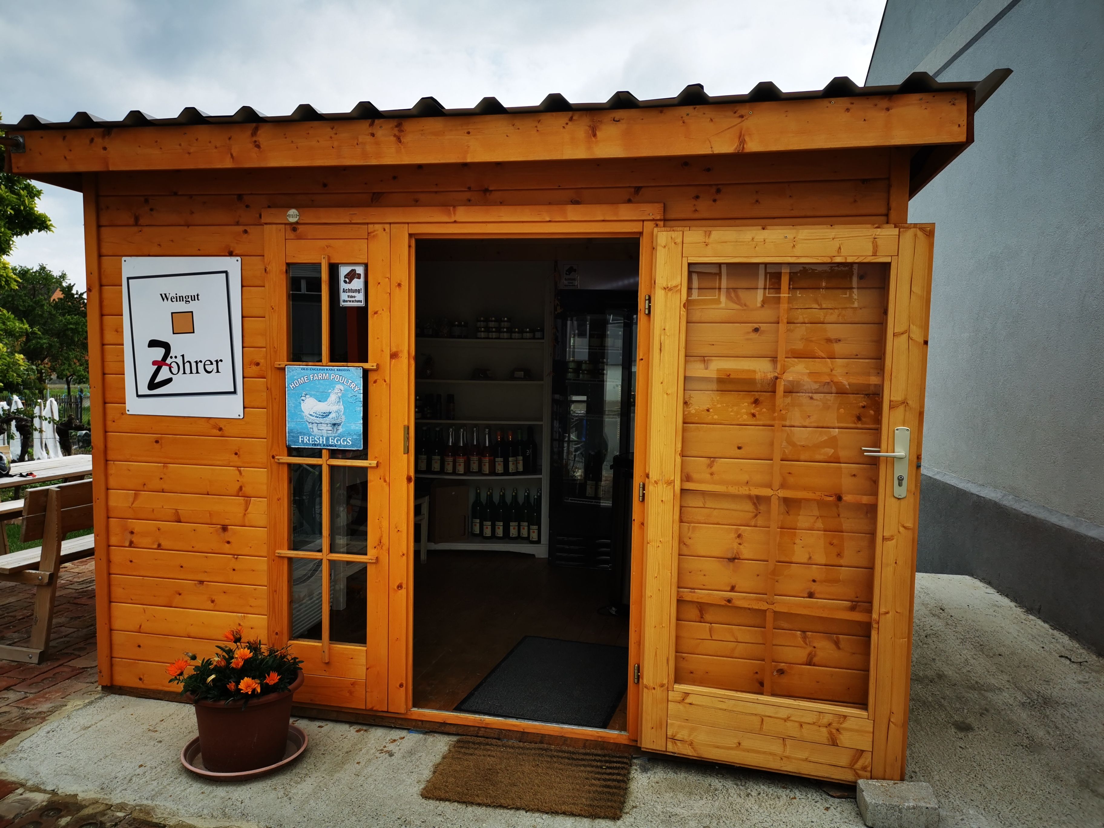 Kleines Holzgebäude mit Schildern des Weinguts Zöhrer und für frische Eier.