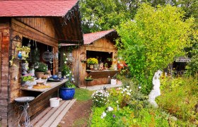 Garten mit Holzh&uuml;tten, Pflanzen und Keramikdekorationen.