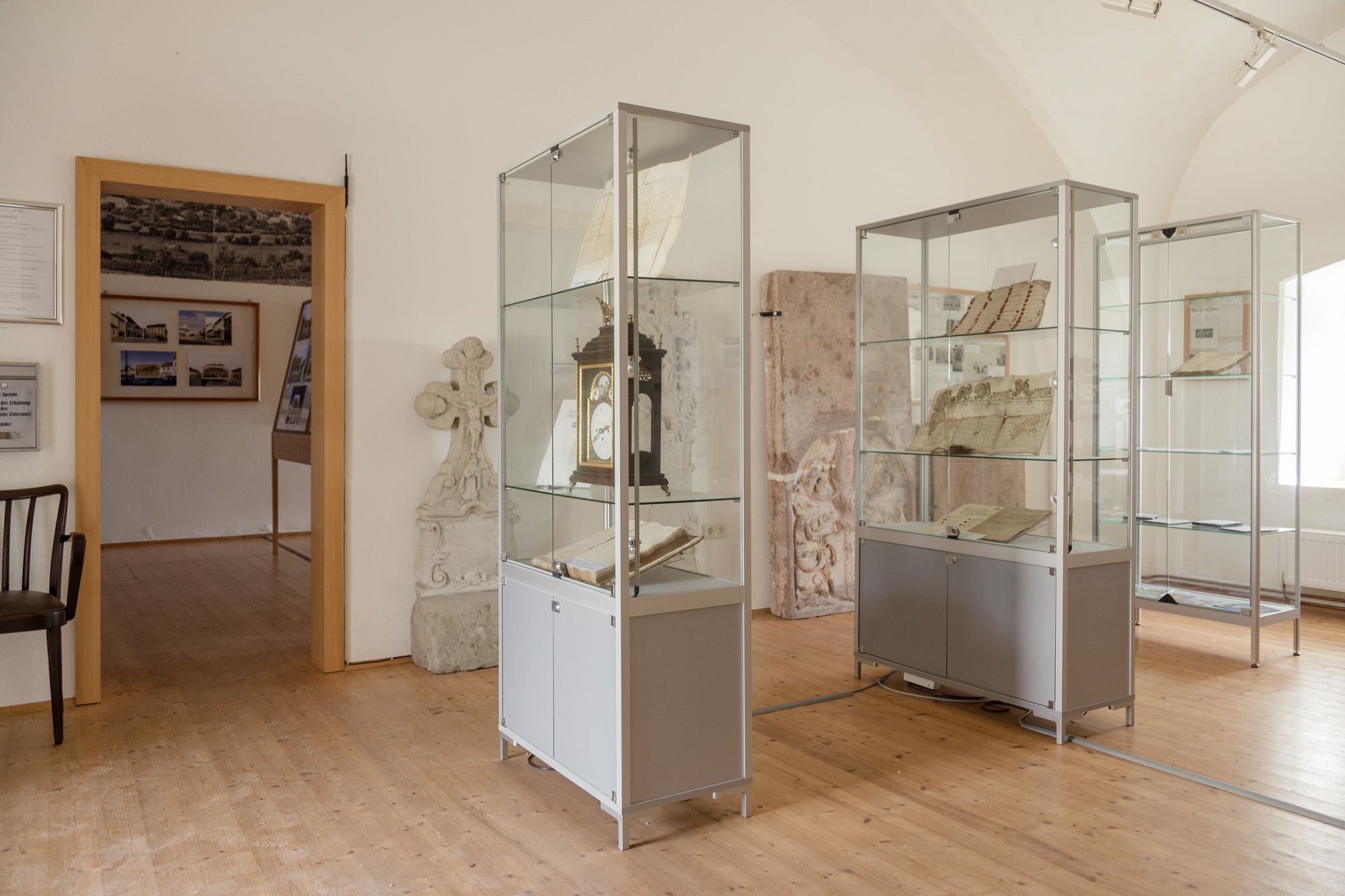 Innenansicht eines Museums mit Vitrinen, die historische Dokumente und Objekte enthalten.