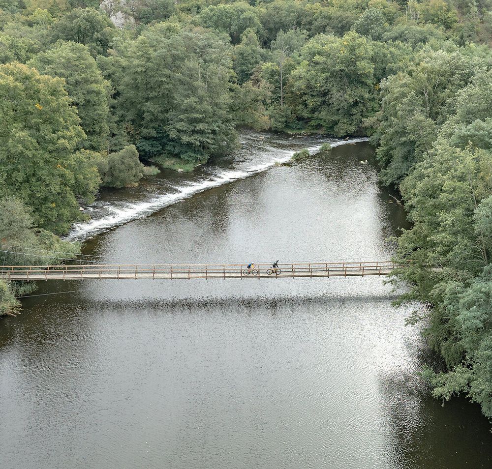 Die Einsiedlerbrücke schwingt sanft über den glitzernden Fluss, umgeben von üppigem Grün und dem beruhigenden Rauschen des Wassers. Radfahrer genießen die malerische Kulisse und die frische Luft, während sie die Schönheit des Nationalparks Thayatal erkunden.