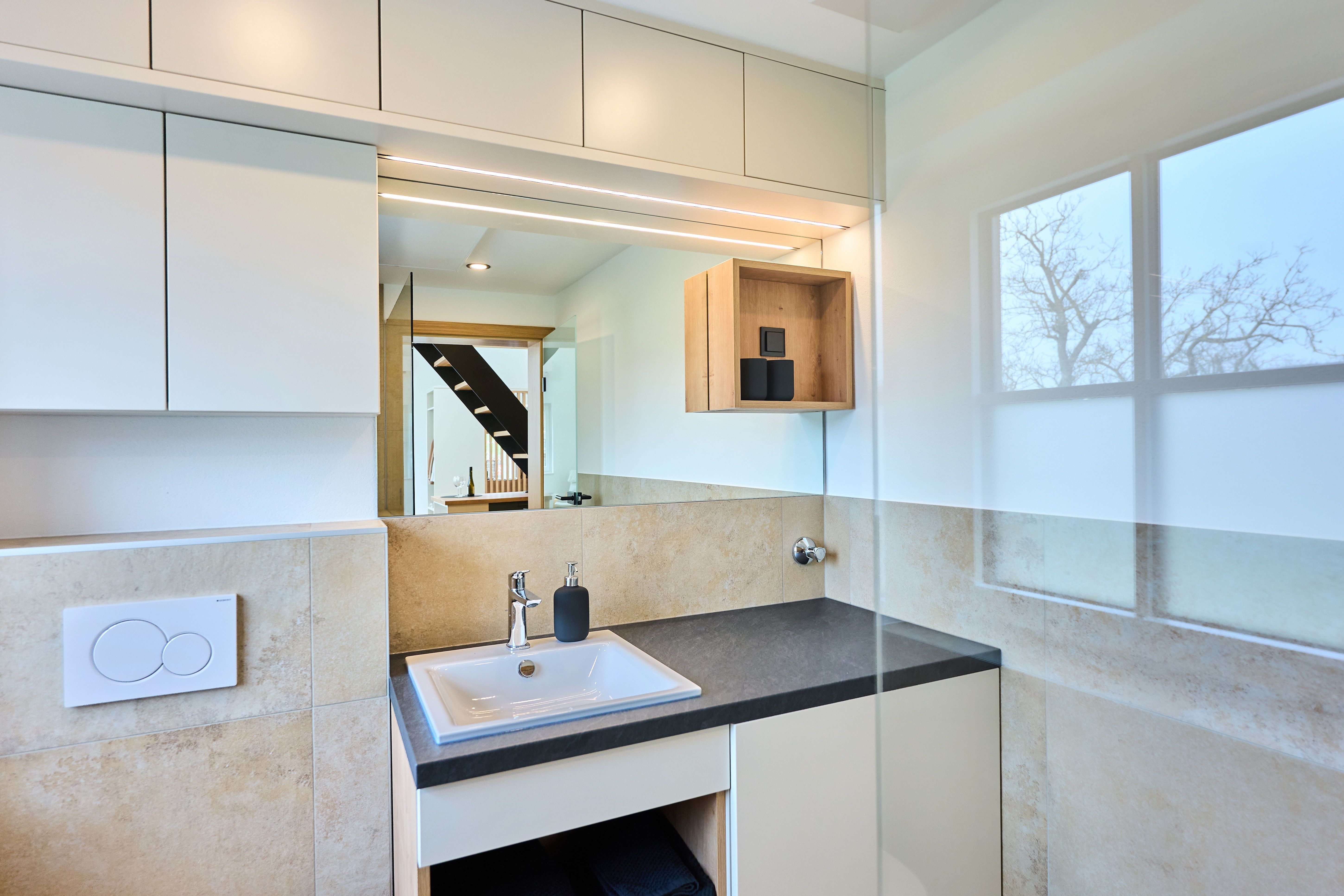 Modernes Badezimmer mit Waschbecken, Spiegel und Fenster.
