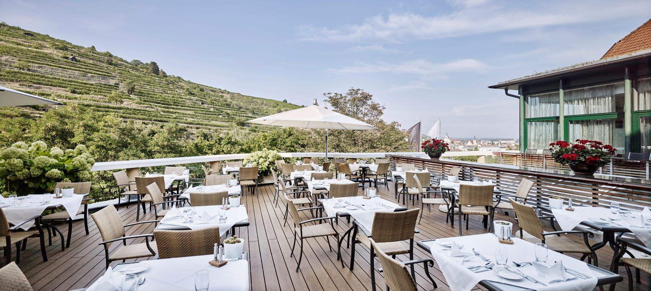Restaurantterrasse mit gedeckten Tischen und Blick auf die Weinberge.
