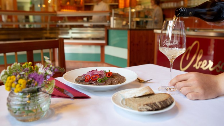 A laid table in a wine tavern with a plate of food, bread and a glass of wine.