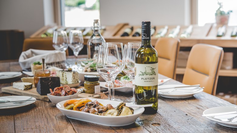 A laid table with a bottle of wine, glasses and various dishes.