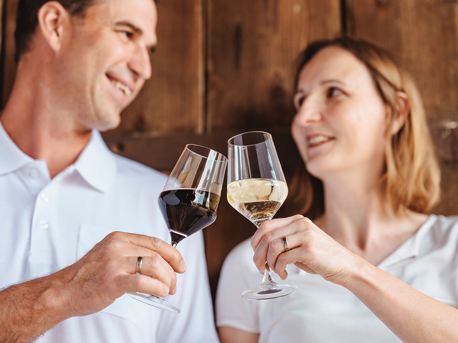 A man and a woman clink glasses of wine.