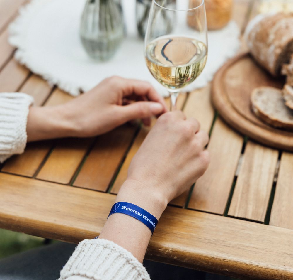 Eine Frau mit Strohut riecht an einem Glas Weißwein.