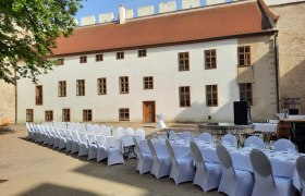 Langer, festlich gedeckter Tisch im Innenhof eines historischen Gebäudes.
