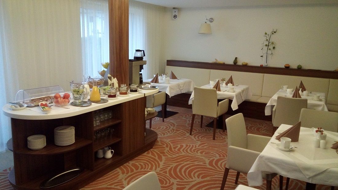 Ein Frühstücksraum mit gedeckten Tischen und einem Buffet mit Speisen und Getränken.