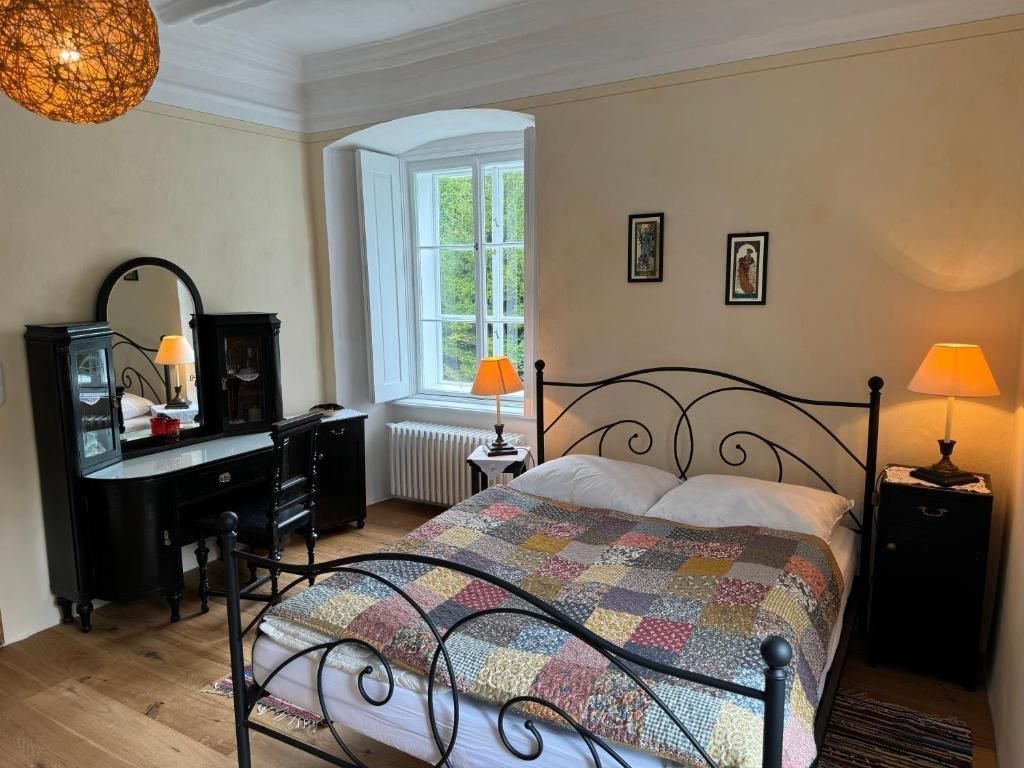 Gemütliches Gästezimmer mit Doppelbett, antikem Schminktisch und warmem Licht.