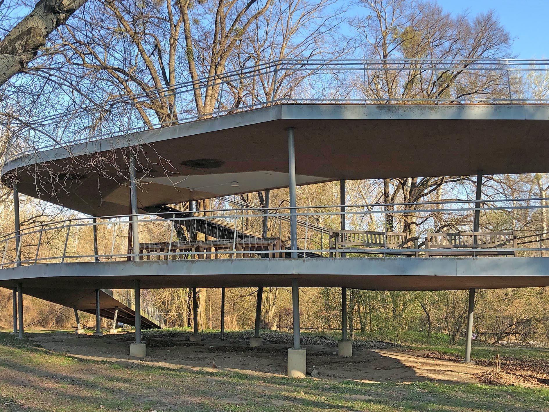Modern terrace with two levels and railings in a wooded area.